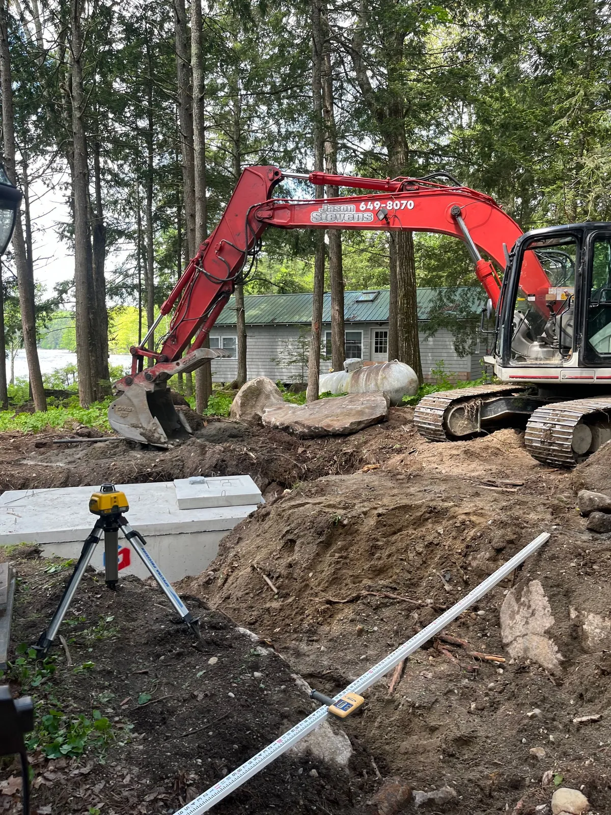 An excavated drainage trench with pipe and stone on a Maine property.